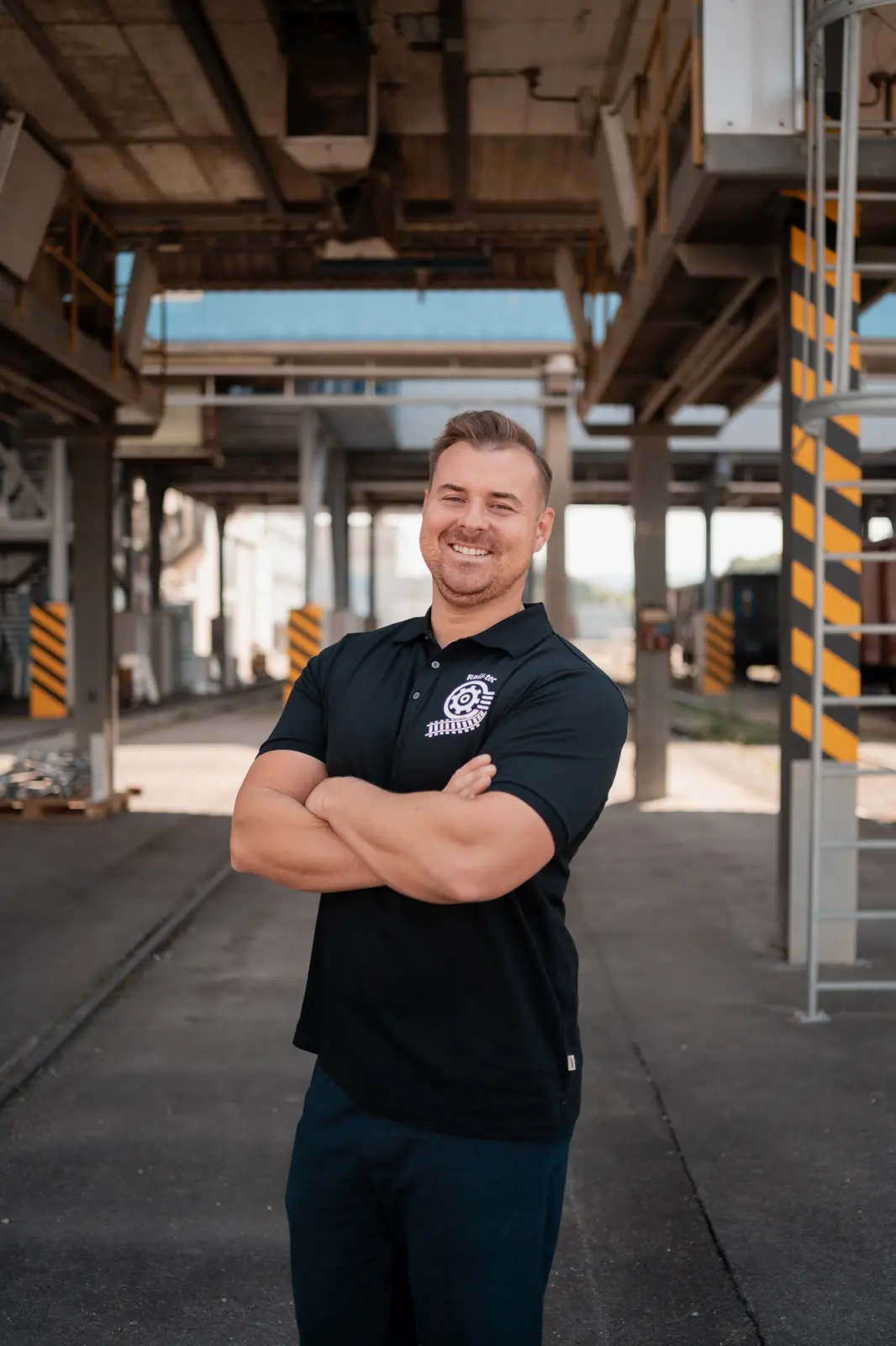 A Rail-tec member of staff in the company polo shirt, under the canopy of a loading hall.